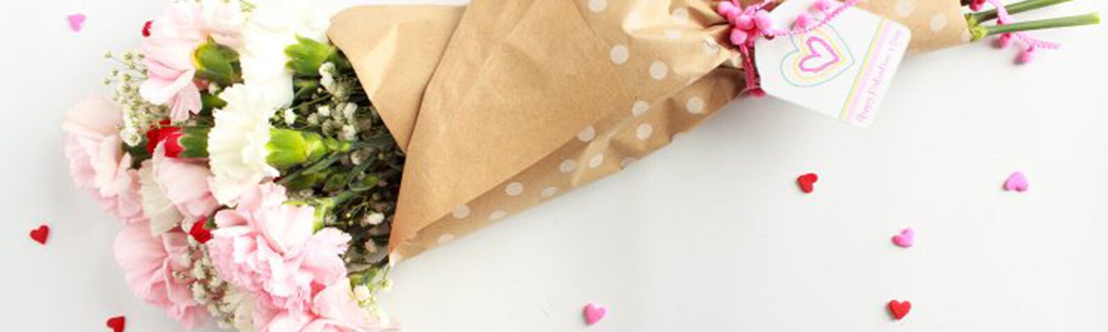 Pink, white, and red carnations flowers wrapped in brown tissue paper as a boutquet