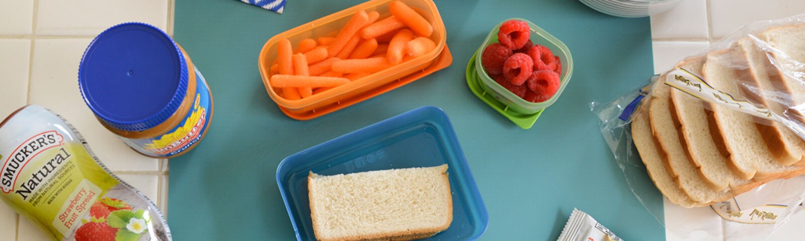 Lunch prep with a peanut butter and jelly sandwich, fruits and vegetables in reusable packing containers
