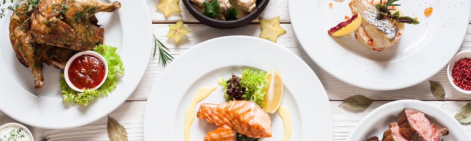 A table covered in various delicious dishes, from a roasted chicken to grilled salmon 